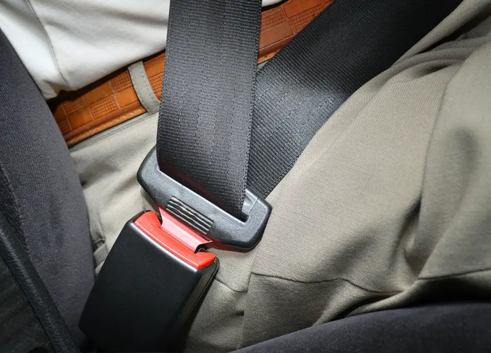 Seat belt fastened across an occupant's lap in a vehicle with a fabric seat